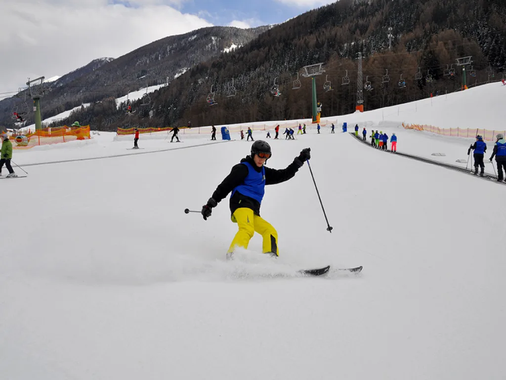 Jugendlicher in gelber Hose zieht einen Schwung auf der Piste.